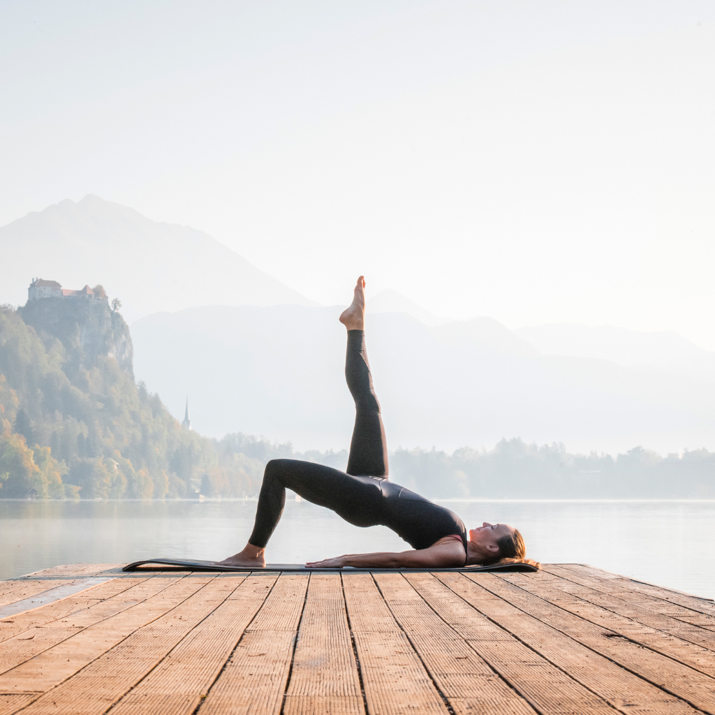 a person doing yoga on a dock in front of a lake