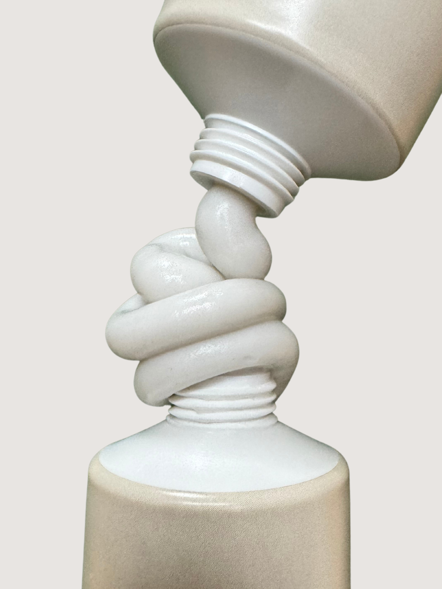Two beige toothpaste tubes squeezing out toothpaste