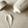 Etinour essential whitening toothpaste tube, formula and cap on beige stone
